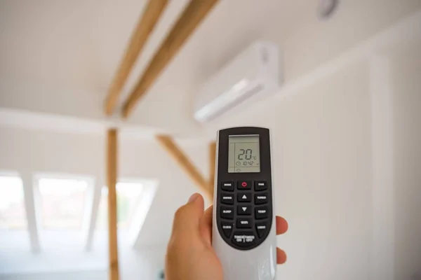 Man adjusting and regulating temperature on home air conditioner with remote control