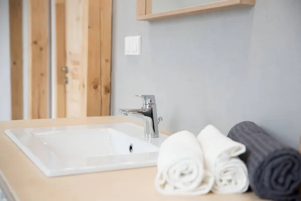 White modern wash basin and towels in hotel bathroom with grey walls