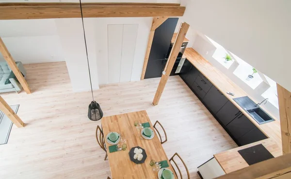 Top view on set wooden dining table. Modern bright flat apartment in the attic