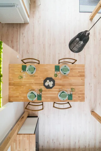 Top view on set wooden dining table. Modern bright flat apartment in the attic