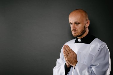 Katolik rahip beyaz cüppe içinde meditasyon ve dua ediyor