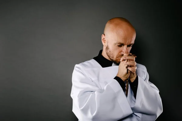 天主教神父在白色斜叠襟和黑色衬衫祈祷与木念珠 — 图库照片