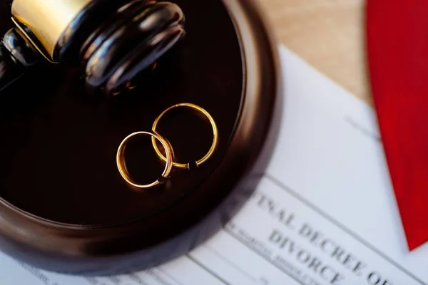 Two broken golden wedding rings on judge gavel. Divorce and separation concept