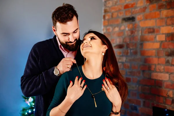 Man helps his wife to wear jewelry necklace. Puts necklace on her neck