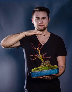 Japon bonsai ağacı tutan genç adam. Çevre koruma kavramı