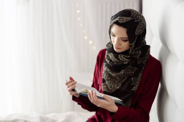 Yatak odasında bir kitap okuma Türban Arap kadın