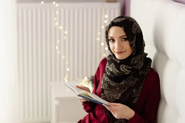 年轻的阿拉伯女人在头巾阅读一本书在卧室里 — 图库照片