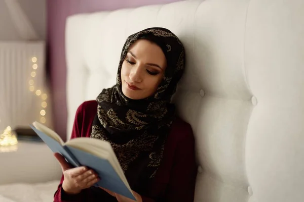 阿拉伯妇女在头巾阅读一本书在卧室里 — 图库照片
