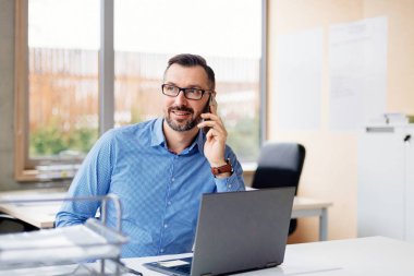 ofiste dizüstü bilgisayar üzerinde çalışan 40 yaşında orta yaşlı yakışıklı adam. Ofiste çalışan adam
