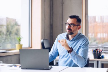 Orta Ofis dizüstü bilgisayar üzerinde çalışan tişörtlü yakışıklı adam yaşlı. Ofiste çalışan adam