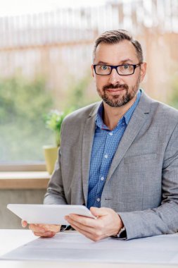 40 yaşında yakışıklı işadamı Office tablet bilgisayarda çalışıyor. Ofiste çalışan adam