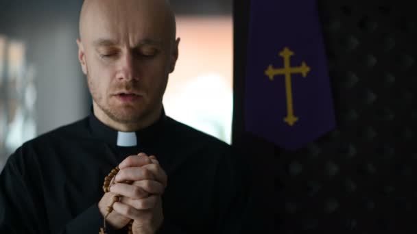 Νέοι Καθολικό Ιερέα Μαύρο Πουκάμισο Προσεύχεται Και Κρατώντας Ξύλινα Ροδάριο — Αρχείο Βίντεο