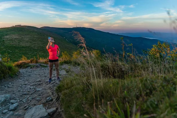 Woman drinking water during running in mountains at summer. Woman running. Silesian Beskid, Szczyrk