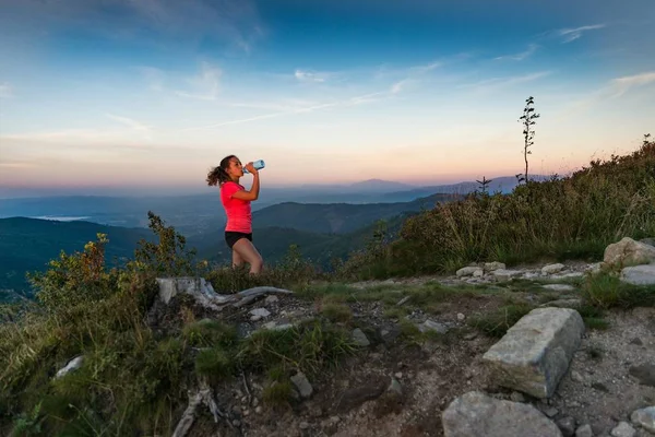 Woman cross country runner drinking water in mountains at summer. Woman running. Silesian Beskid, Szczyrk