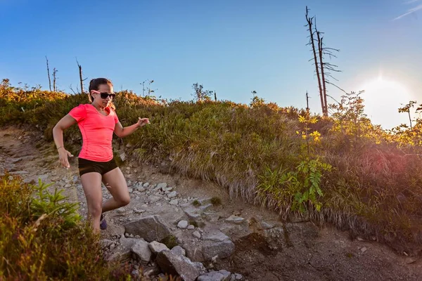 Young woman trail running in mountains at summer. Woman running