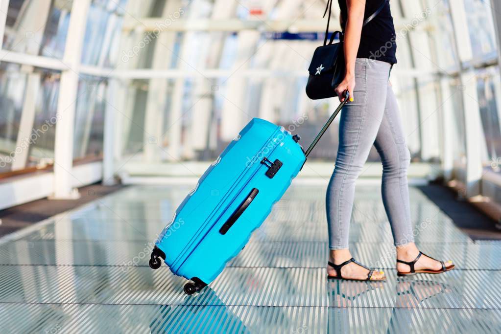 Woman with blue baggage suitcase on train station.