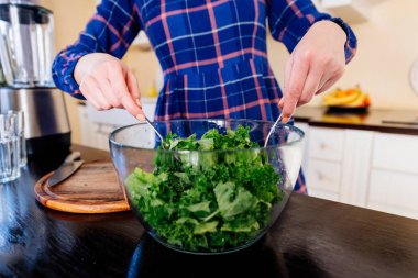 Kadın mutfakta bir cam kasede yeşil lahana karıştırma