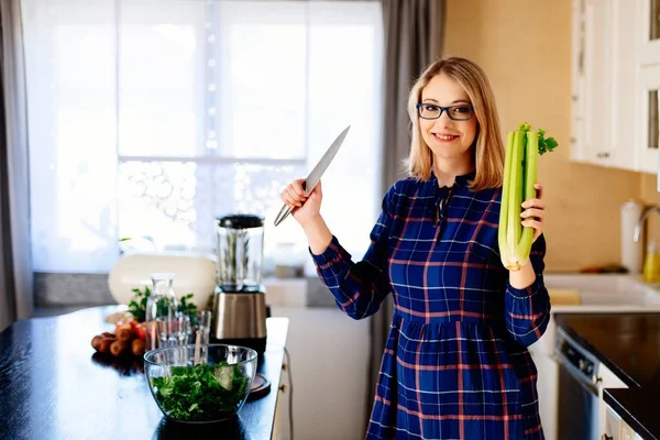 Mujer con apio y cuchillo en cocina — Foto de Stock