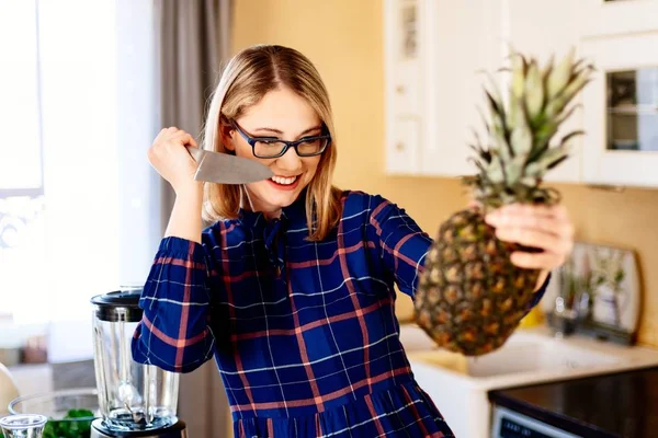 Junge Frau öffnet Ananas mit Messer in Küche — Stockfoto