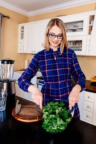 Woman mixing green kale in a glass bowl in kitchen — Stock Photo, Image