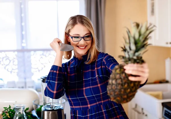 Woman opening pineapple with knife in kitchen — Stock Photo, Image