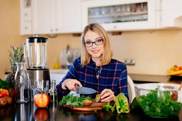 Frau schneidet Kiwi-Früchte in Küche. — Stockfoto