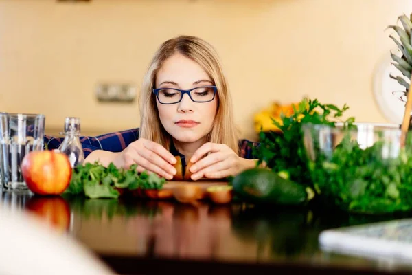 Woman with two kiwi halves in the kitchen. — Stock Photo, Image