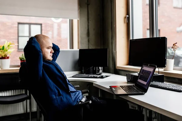Расслабленный человек, работающий в офисе на ноутбуке — стоковое фото