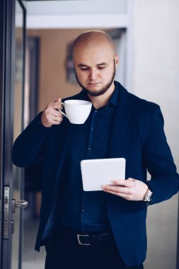 Dijital tablet tutarak ve ofiste bir kahve içme genç işadamı