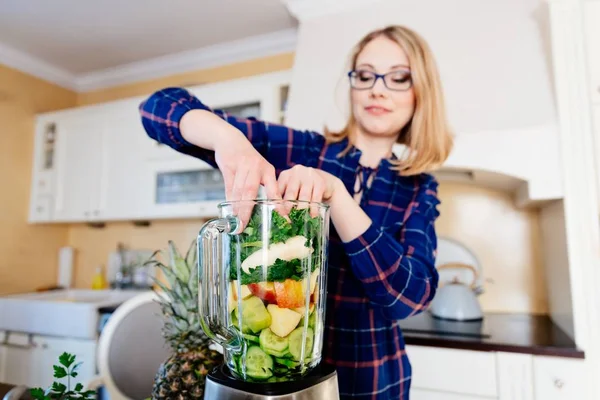 Женщина кладет фрукты и овощи в элетрический блендер . — стоковое фото