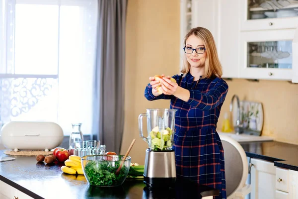 Junge Frau legt Obst und Gemüse in den Mixer — Stockfoto