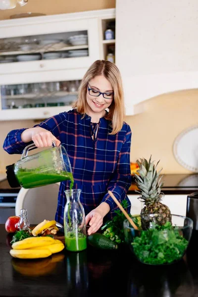 Young happy pregnant woman pouring green smoothie to glass cup — Stock Photo, Image