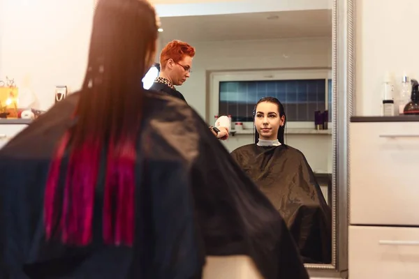 Mulher cabeleireiro secagem jovem mulher cliente cabelo no salão — Fotografia de Stock