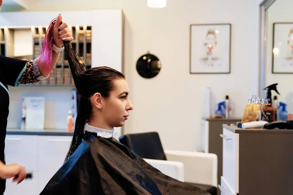 Woman hairdresser styling young woman customer hair in salon