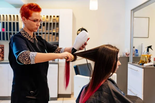 Cabeleireiro secagem mulher cabelo com secador de cabelo . — Fotografia de Stock