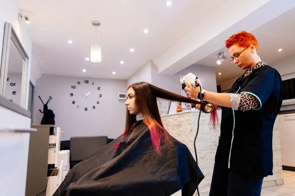 Cabeleireiro secagem mulher cabelo com secador de cabelo . — Fotografia de Stock