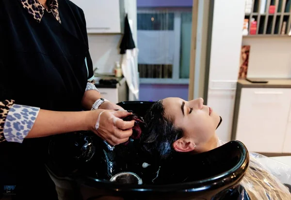 Перукарська мийка жіночого волосся клієнта в салоні . — стокове фото