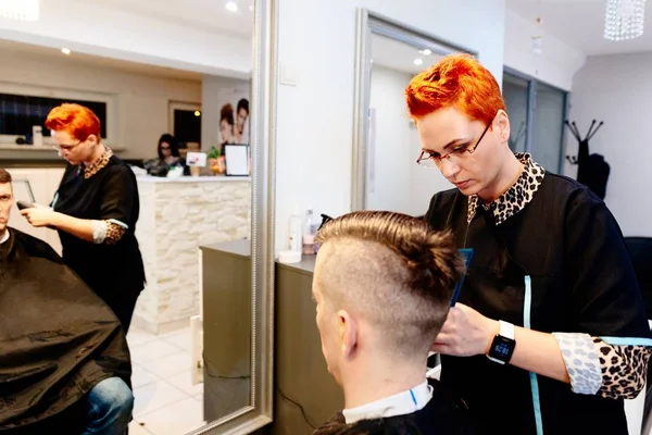 Vrouw Kapper snijden mannelijke klant haar met elektrische trimmer. — Stockfoto