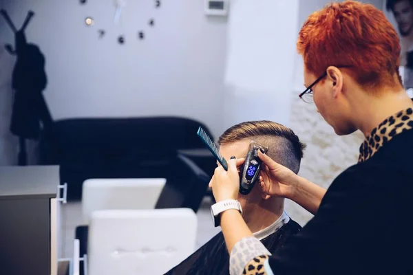 Cabeleireiro mulher corte cabelo cliente masculino com aparador elétrico . — Fotografia de Stock