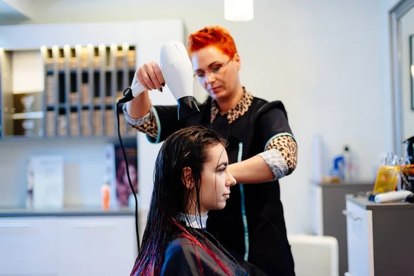 Cabeleireiro mulher secando o cabelo do cliente com secador de cabelo — Fotografia de Stock