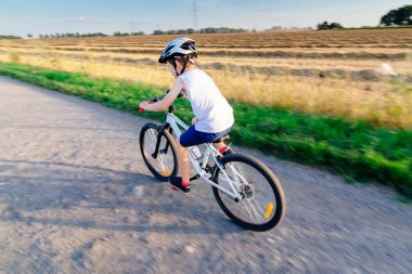 Çocuk onun bisiklet sürme beyaz kask içinde.