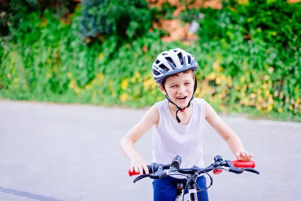 Menino feliz criança no capacete branco na bicicleta — Fotografia de Stock
