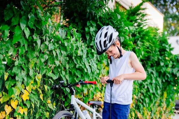 Niño feliz en casco blanco inflando neumático en su bicicleta —  Fotos de Stock