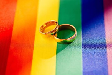 Gökkuşağı LGBT bayrağı iki altın alyans. Homoseksüel evlilik.