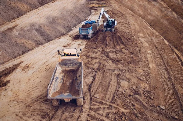 ティッパートラックに砂を積み込む掘削機上の空中ドローンビュー. — ストック写真