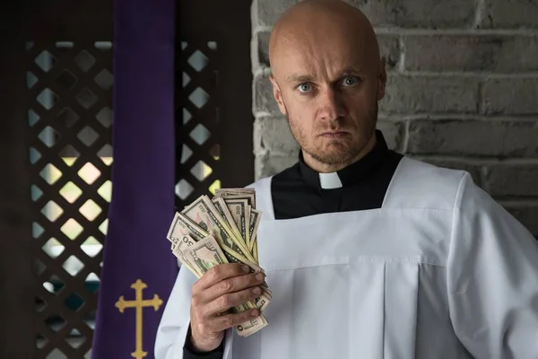 Catholic priest with money in his hand