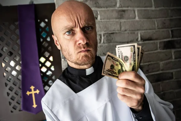 Sacerdote católico con dinero en la mano — Foto de Stock