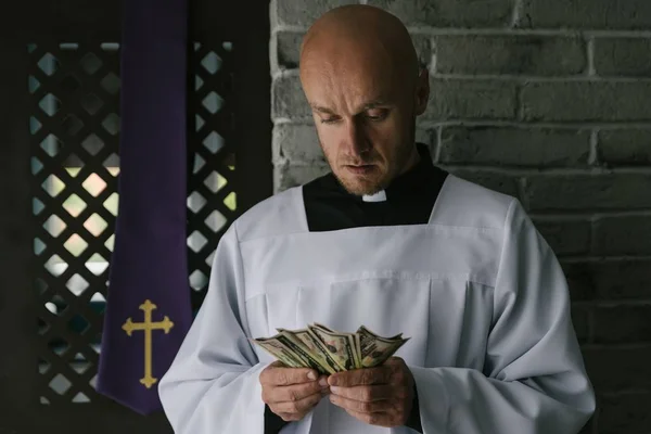 Ksiądz katolicki liczący pieniądze w ręku — Zdjęcie stockowe