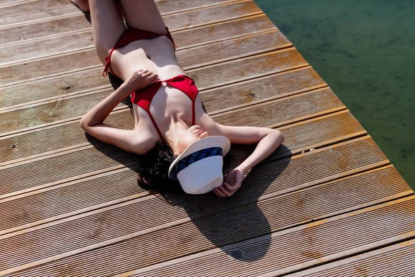 Donna in costume da bagno rosso prendere il sole sul molo del mare — Foto Stock
