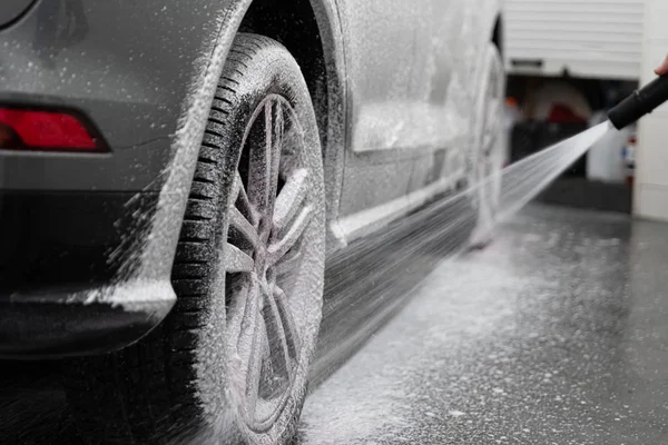 Lavatrice auto spruzzando ruota auto e pneumatico con schiuma bianca pulizia attiva — Foto Stock